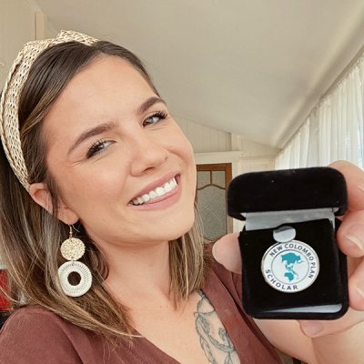 Adele holding her Colombo Plan Scholar medal and smiling at the camera 